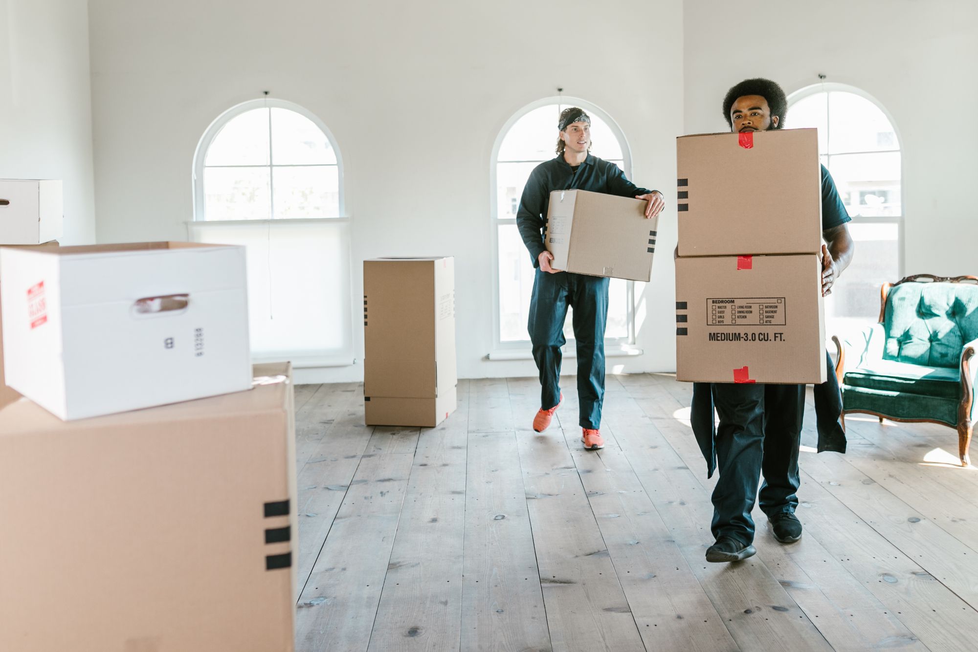 Umzugsteam trägt Kartons in eine helle Wohnung